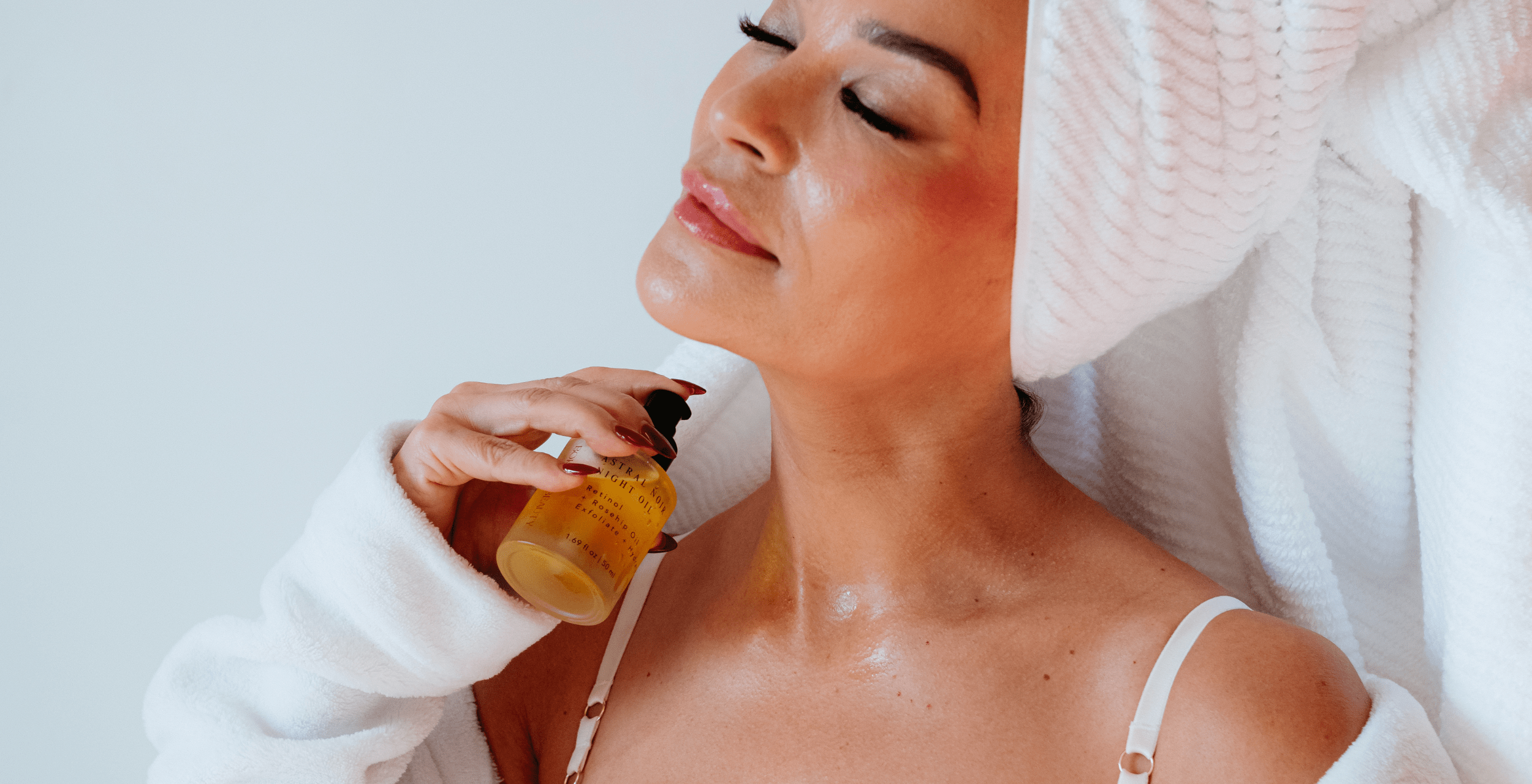 Woman applying oil to her face with a white background
