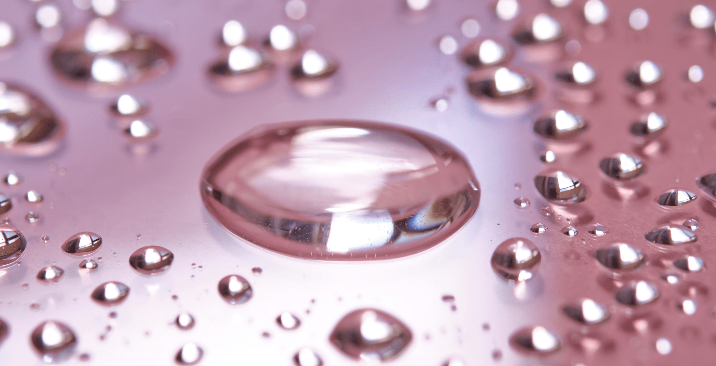 Close-up of a ring with water droplets on a pinkish-purple background