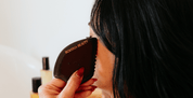 Person using a black makeup brush with 'Boscia Beauty' branding on a blurred background.