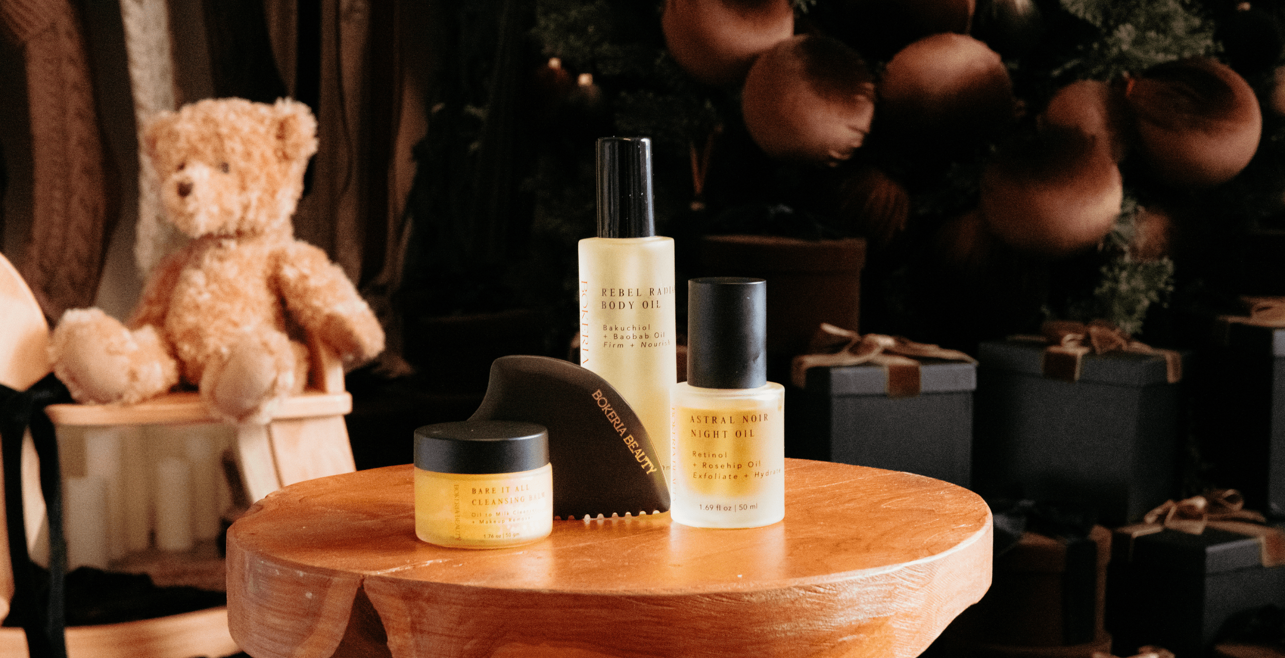 Cosmetic products on a wooden table with a teddy bear and decorative items in the background