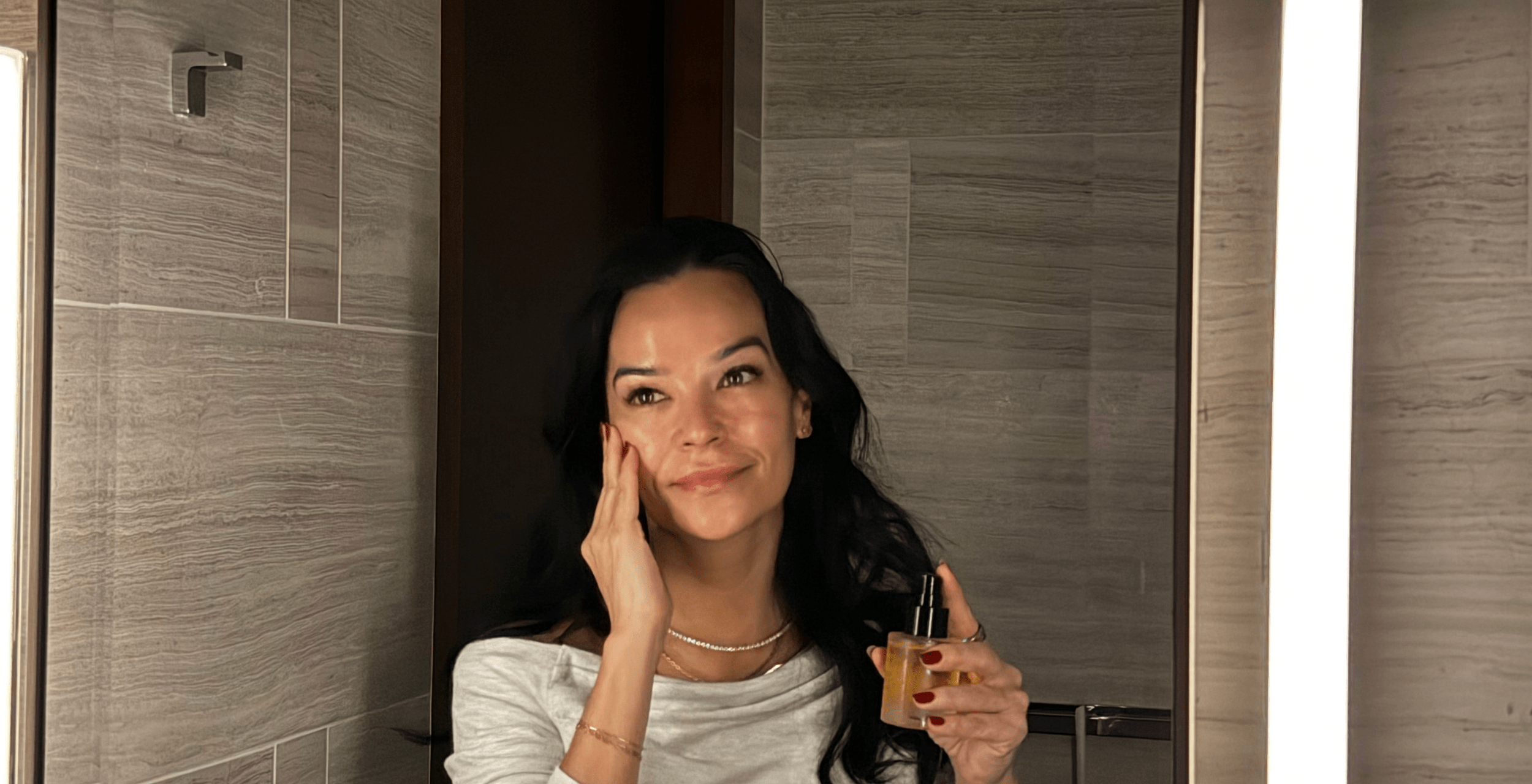 Woman applying astral noir night oil in a bathroom