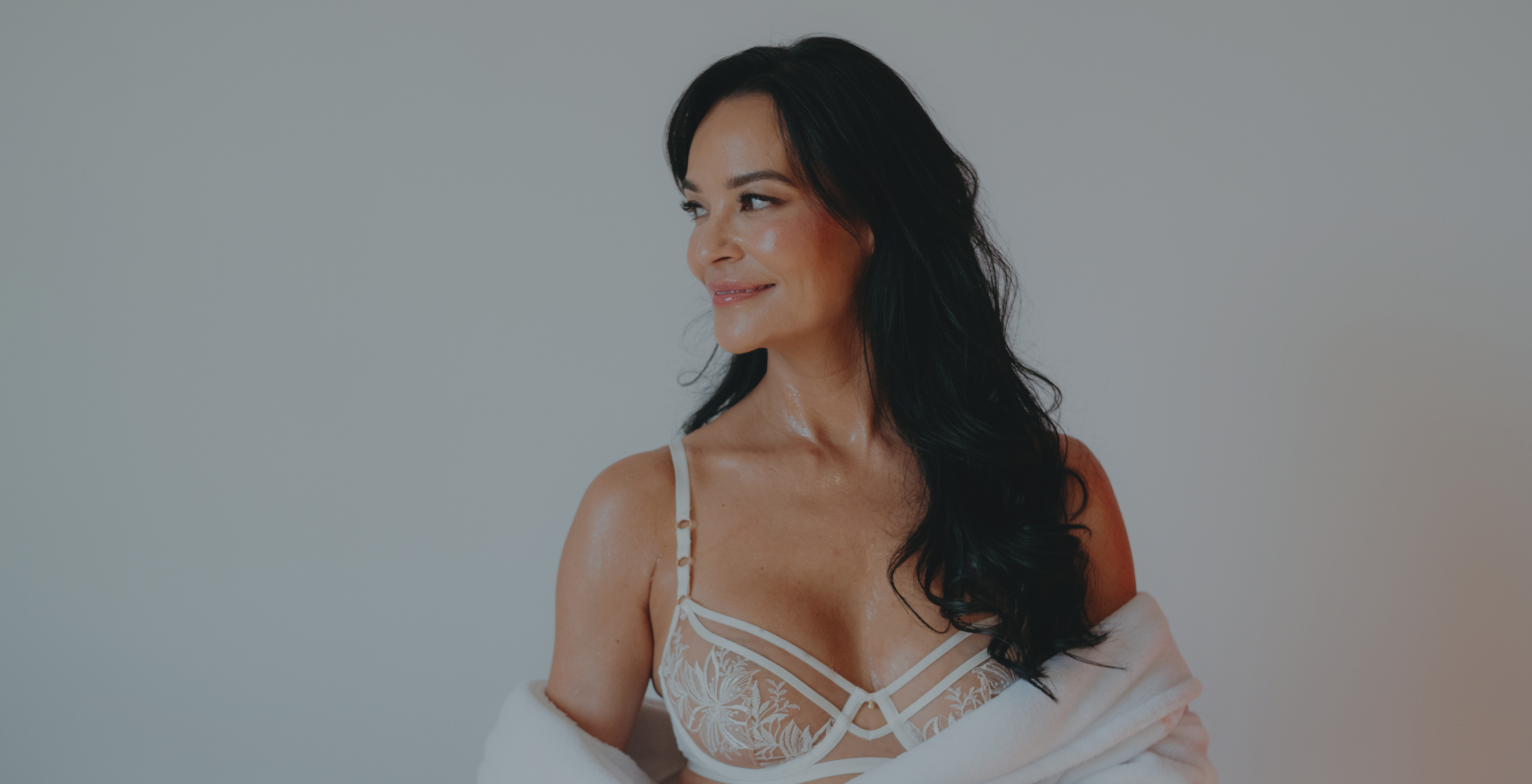 Woman wearing a white lace top against a plain background