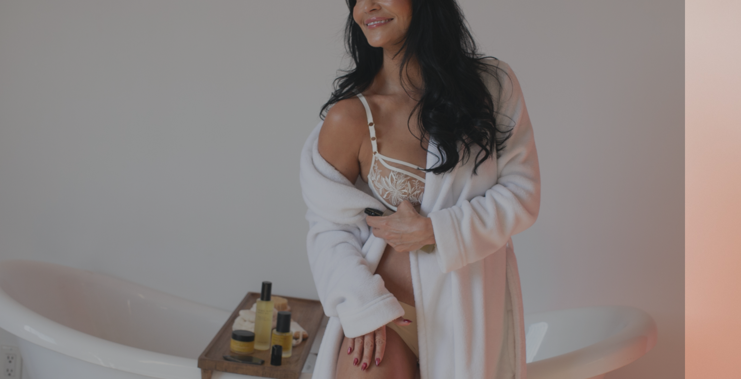 Woman in a robe standing by a bathtub with a tray of items